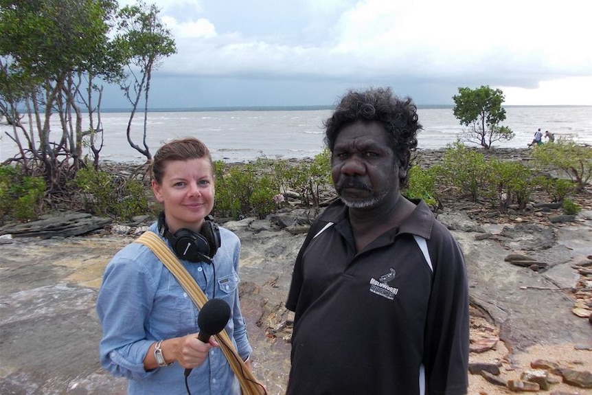 Jane Bardon standing with a microphone outdoors next to traditional owner Joseph Diddo