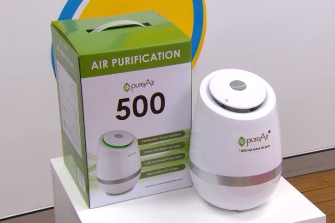 A purifier sits on a table next to its box.