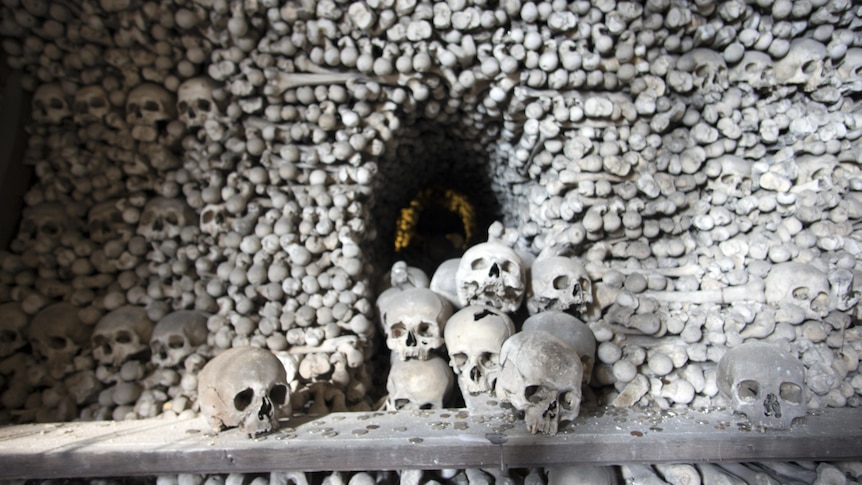A pile of skulls outside a cave made of human bones