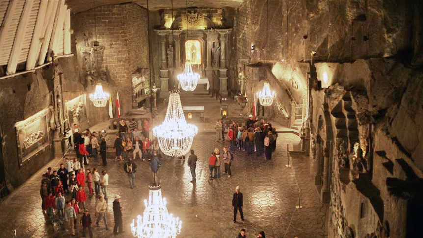 A cavernous space with chandeliers and people