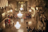 A cavernous space with chandeliers and people