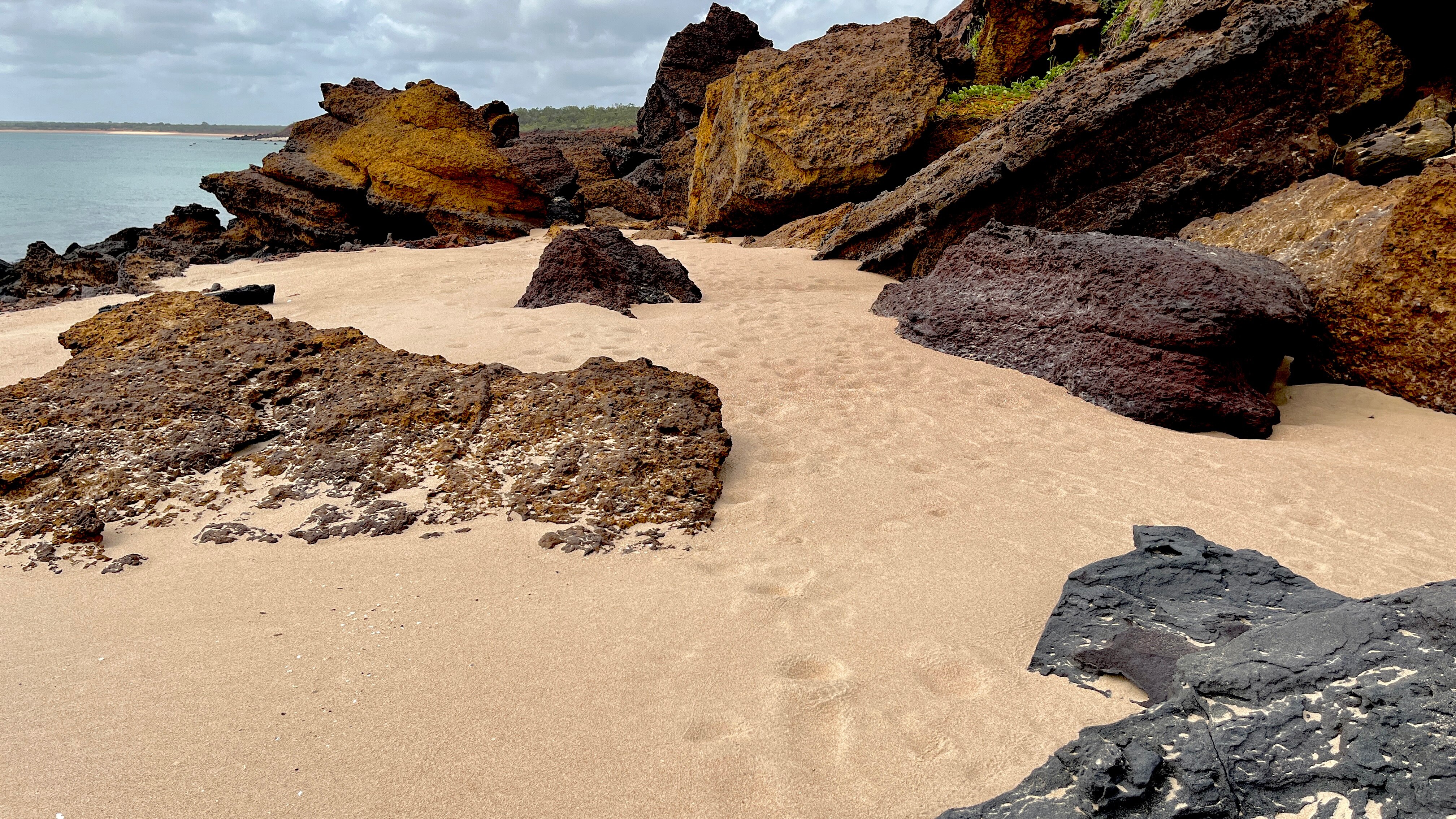 Footprints in sand with large rocks across the landscape.