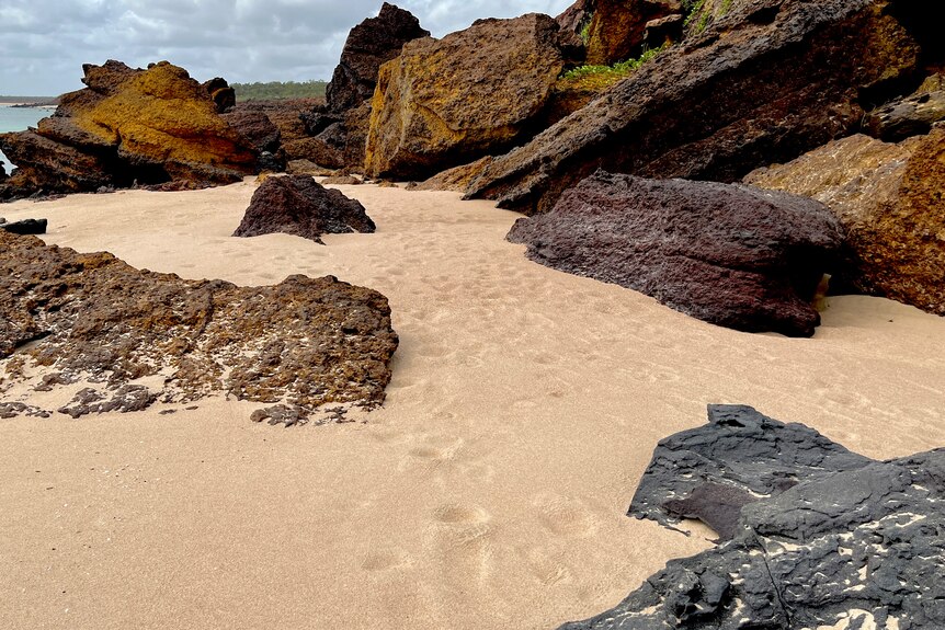 Footprints in sand with large rocks across the landscape.