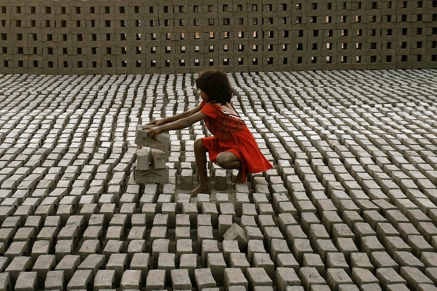 A child labourer in India stacks bricks.