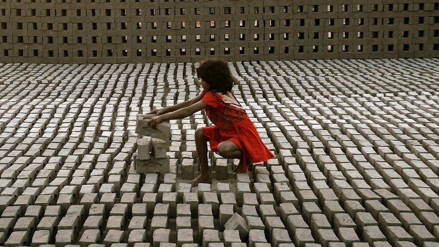 Child labour - young girl stacks bricks in Hyderabad, India