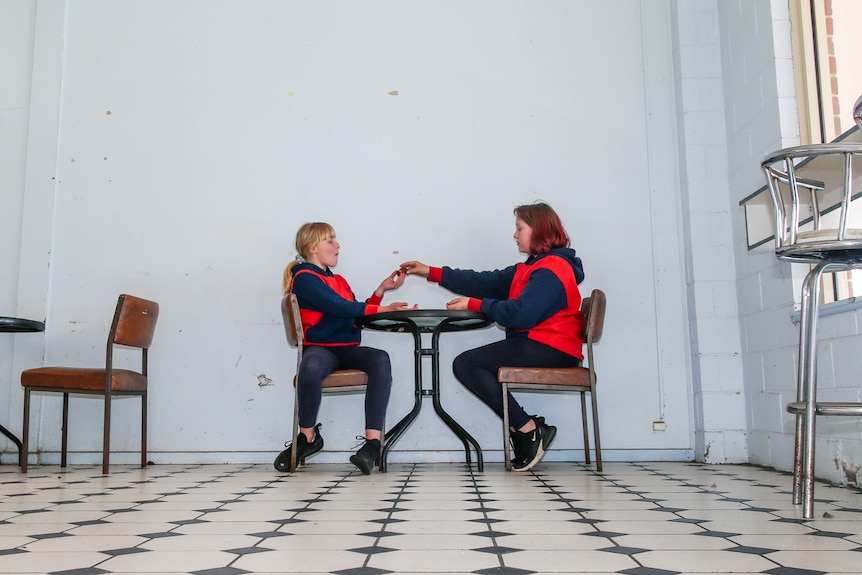 Two girls sit at a table at a milk bar