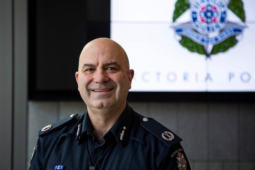 A man with a Victoria Police sign behind him.