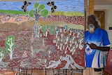 Two Aboriginal men holding artwork depicting sacred land