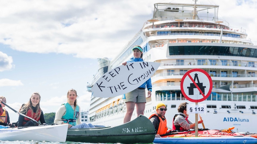 People on canoes on water in front of a cruise ship