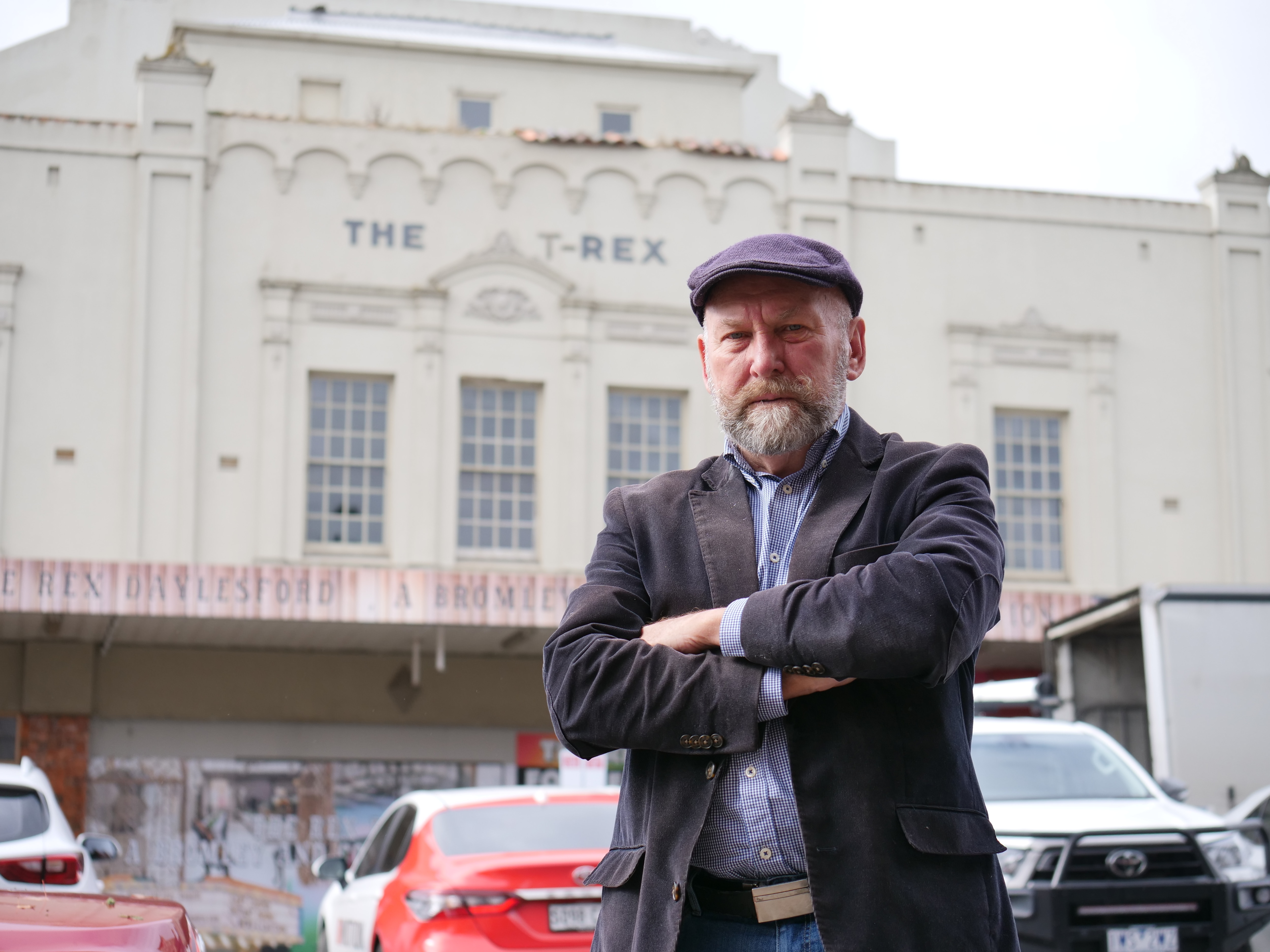 A man stands in front of a building.