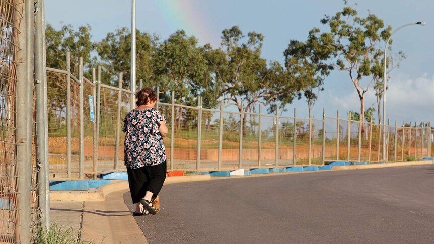 Linda Hyland walking her dog next to a long row of fences.