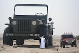 A man standing next to a massive model Jeep next to a normal sized Jeep.