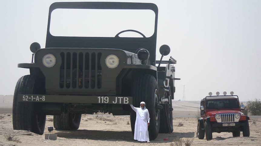 a man standing next to a massive model Jeep next to a normal sized Jeep.