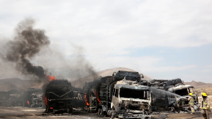 Afghan firefighters spray water on burning NATO supply trucks in Samangan province.