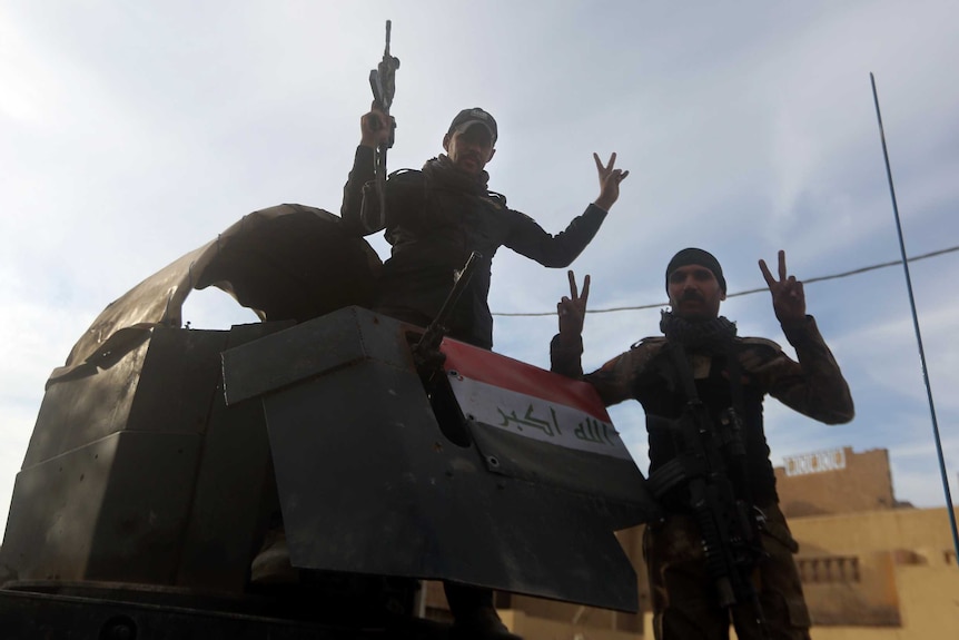 Iraqi military troops holding up peace signs.