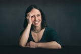 Portrait of a young woman with a green top and shoulder length brown hair