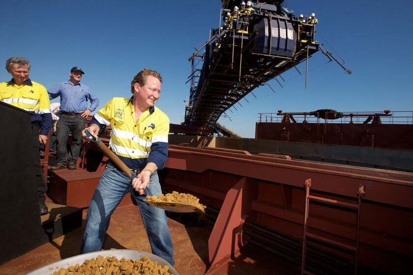 Andrew Forrest shovels a batch of iron ore into the hold of a ship at port.