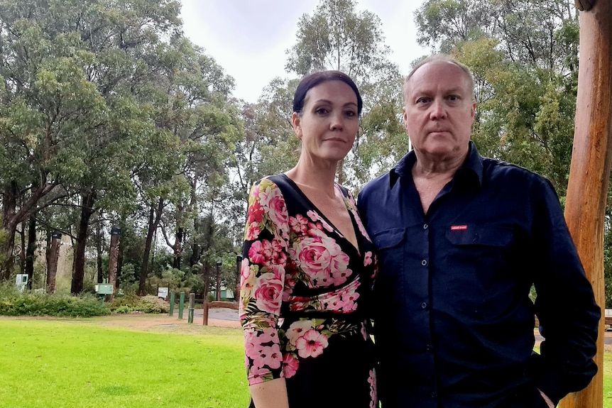 dark haired woman standing next to man in front of natural bushland