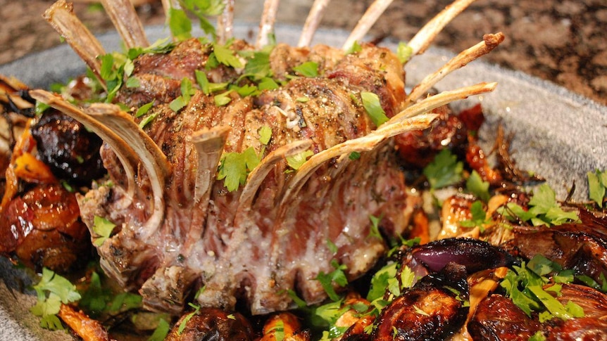 A lamb crown roast surrounded by vegetables.