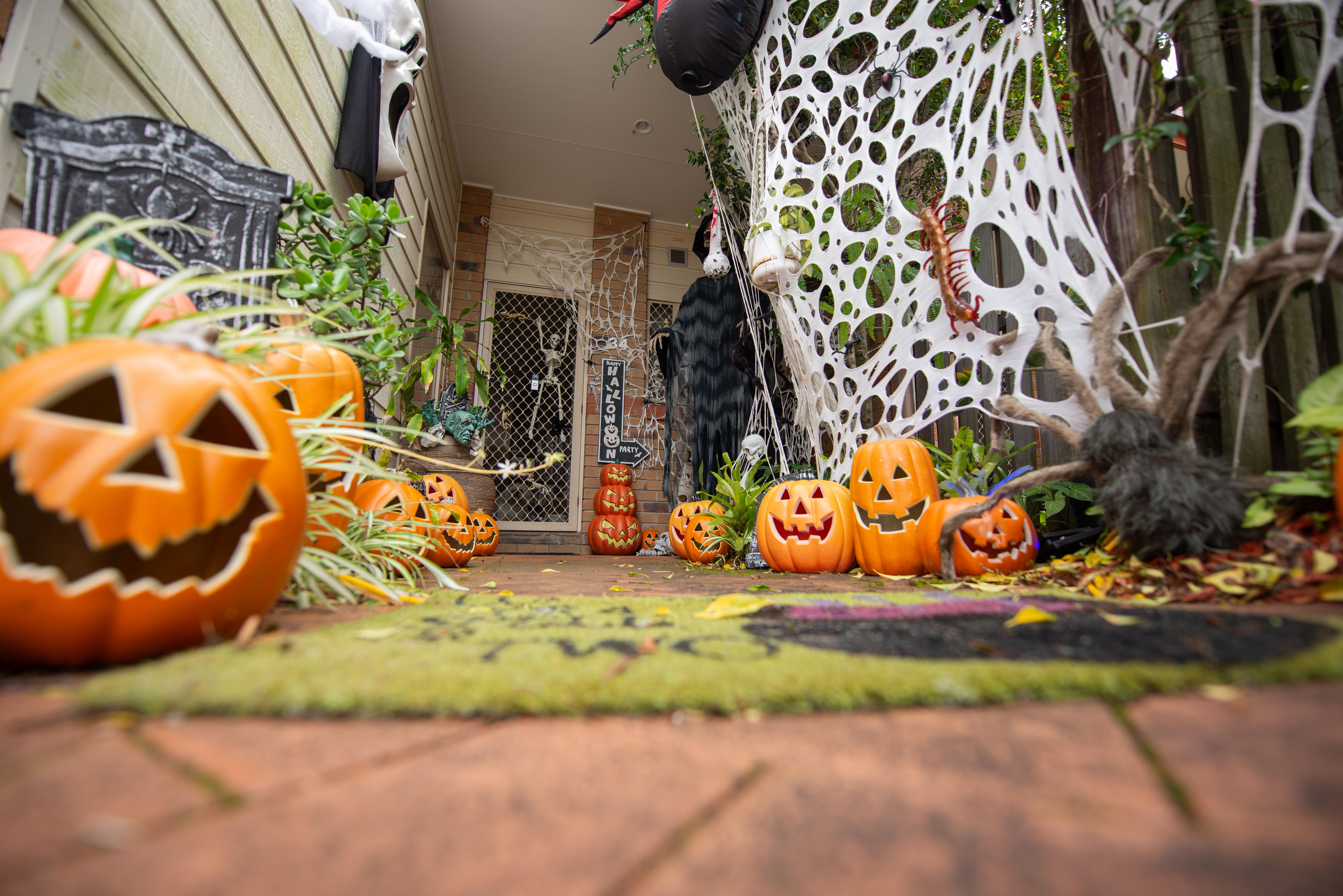 Plastic pumpkins and fake spiders webs line the entry path to a suburban townhouse.