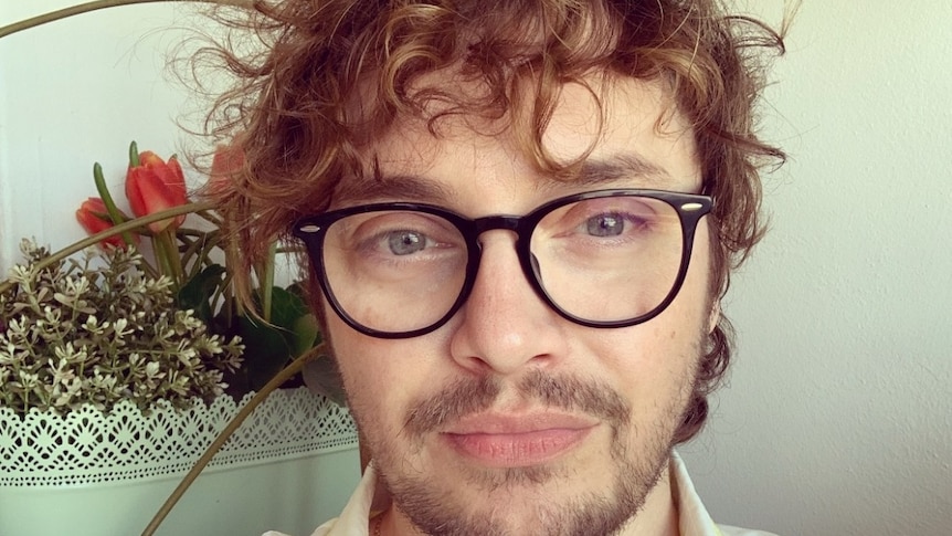 A man with short curly hair and glasses