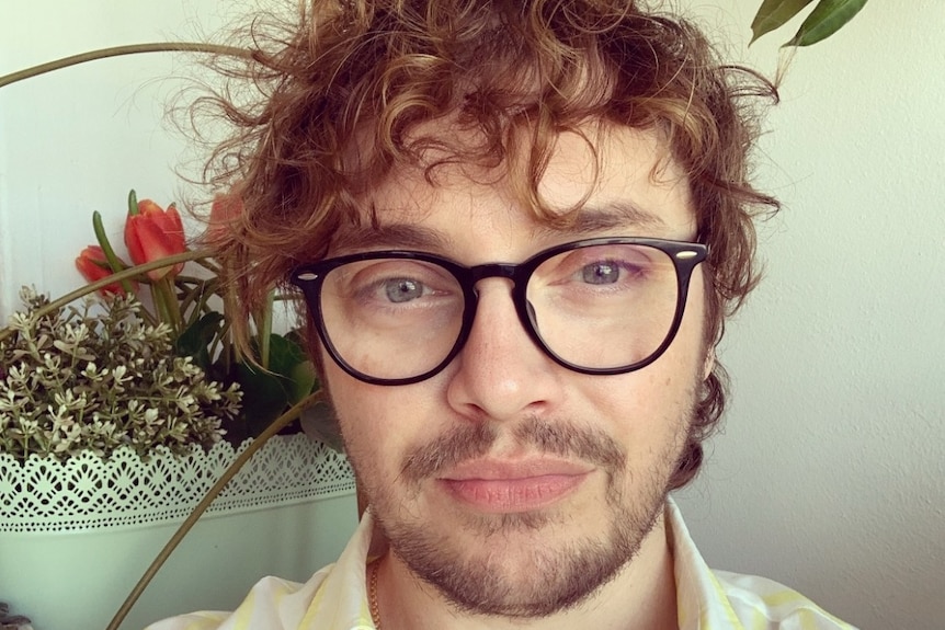 A man with short curly hair and glasses