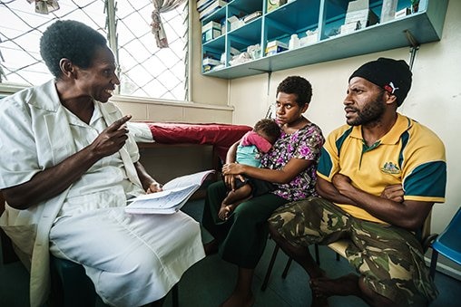 A health adviser talks to a mother and father.