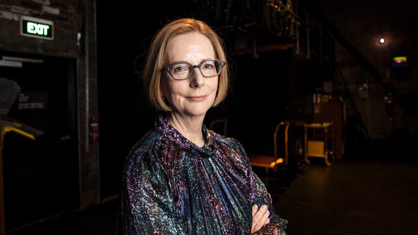 Former prime minister Julia Gillard folds her arms and smiles as she poses for a photo backstage at a theatre