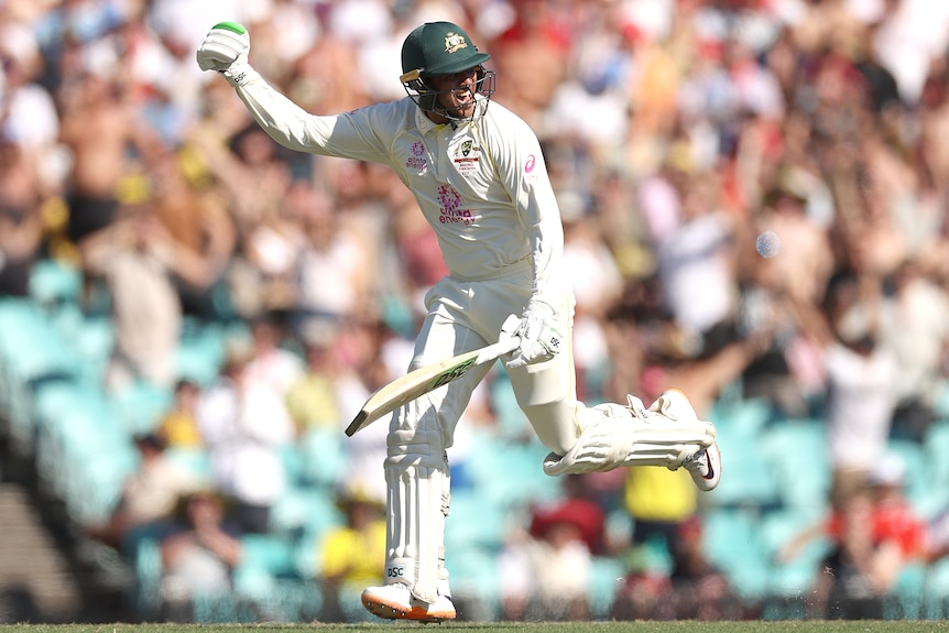 Australia batter Usman Khawaja punches the air as he scores a run during an Ashes Test at the SCG.