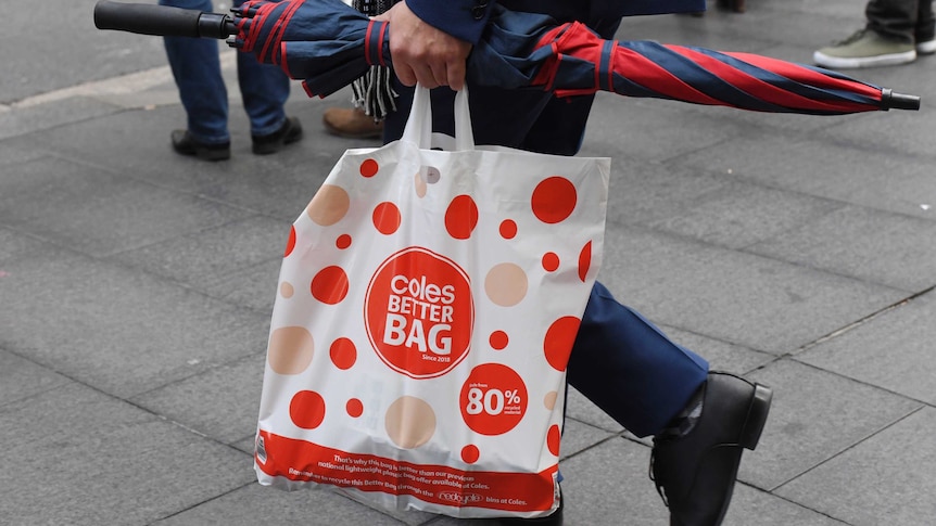 A shopper carries a reusable plastic bag from a Coles store in Sydney.