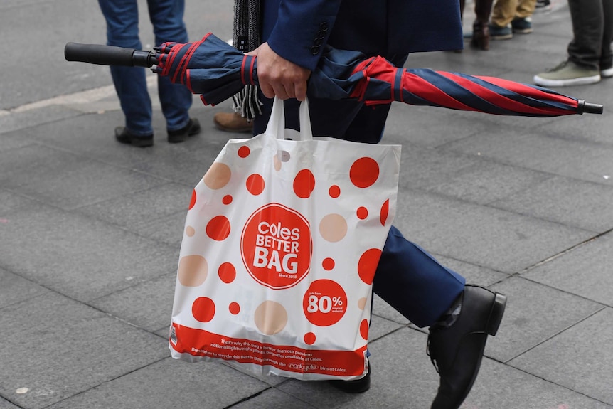 A shopper carries a reusable plastic bag from a Coles store in Sydney.