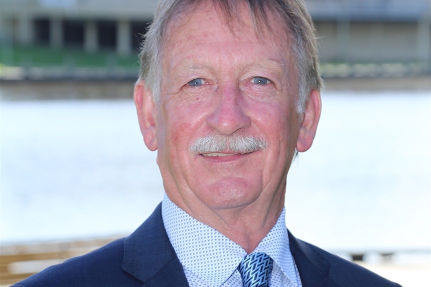 A man in a suit smiles at the camera