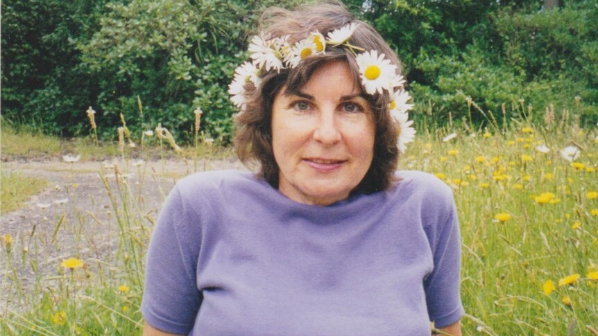 Judith McIntyre sitting on grass with a crown of flowers around her head.