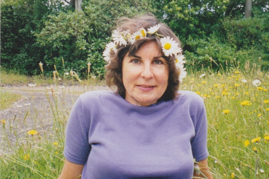 Judith McIntyre sitting on grass with a crown of flowers around her head.