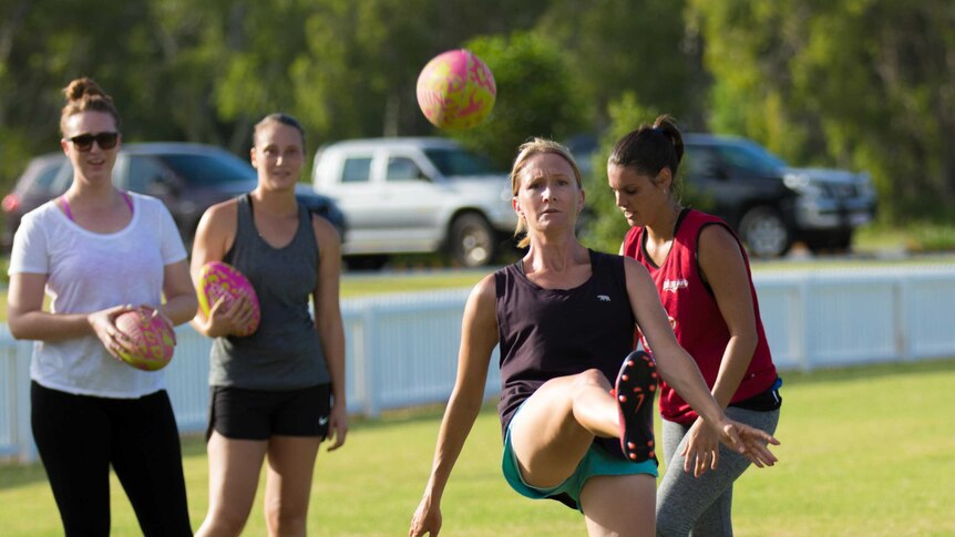 Women in sports clothing practising Australian rules football