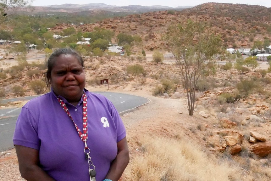 A woman stands in front of rolling country in Central Australia.