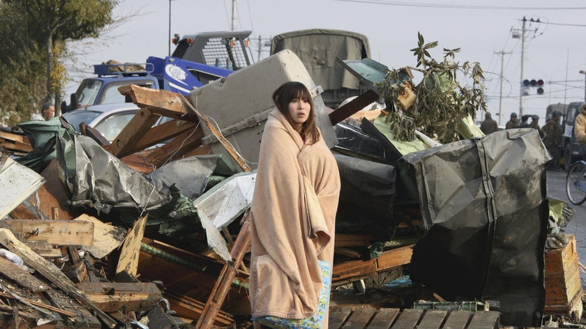 Fears for the future: a stunned woman stands amongst rubble in Ishimaki city after the earthquake