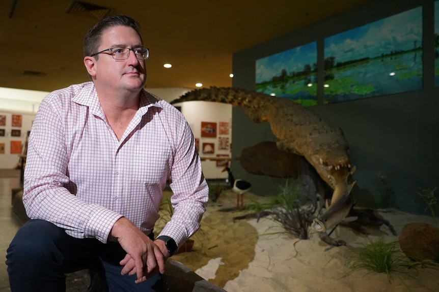 Chris Chaffe is wearing a red and white business shirt and is in a hotel lobby near a stuffed crocodile.