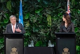 Antonio Guterres stands on a podium next to Jacinda Ardern.