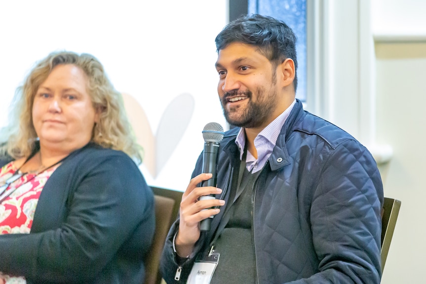 A photo of Ayman Islam holding a microphone at a conference.