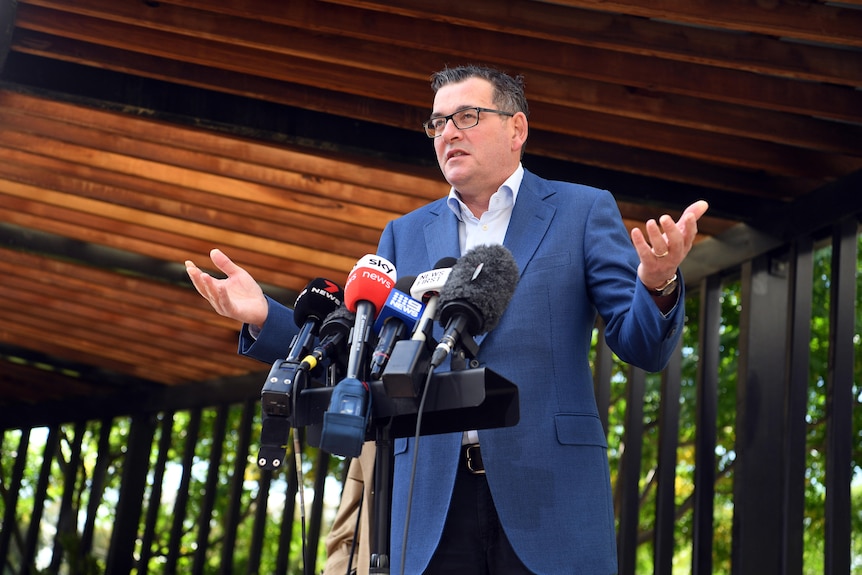 Victorian Premier Daniel Andrews speaks to media during a press conference with his hands outstretched.