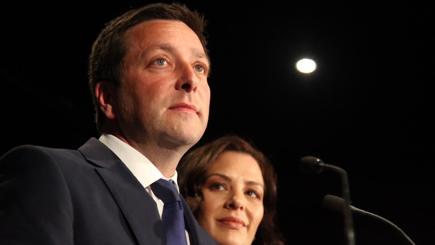 Matthew Guy stands with his wife at a podium.