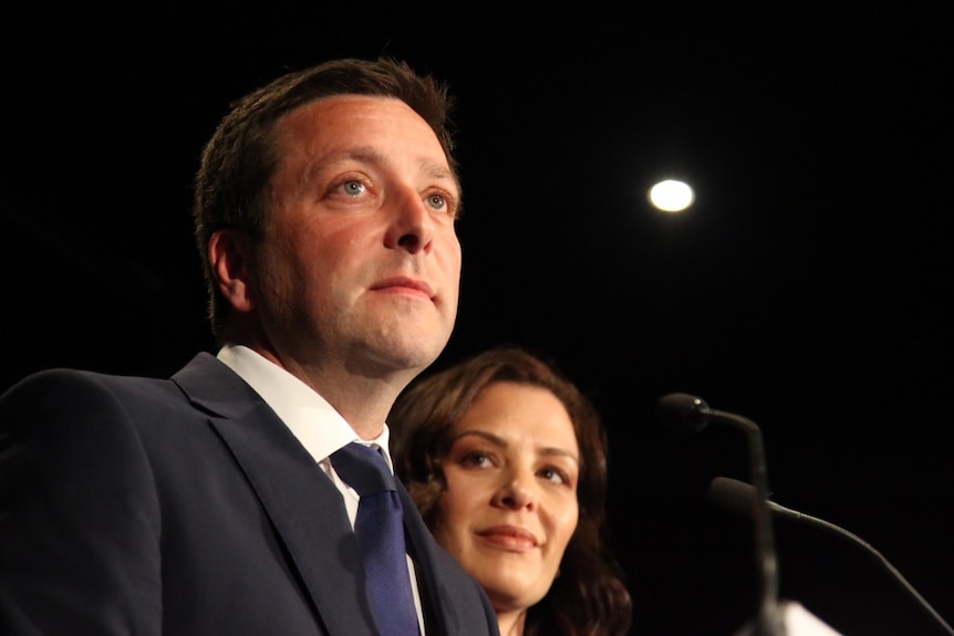 Matthew Guy stands with his wife at a podium.