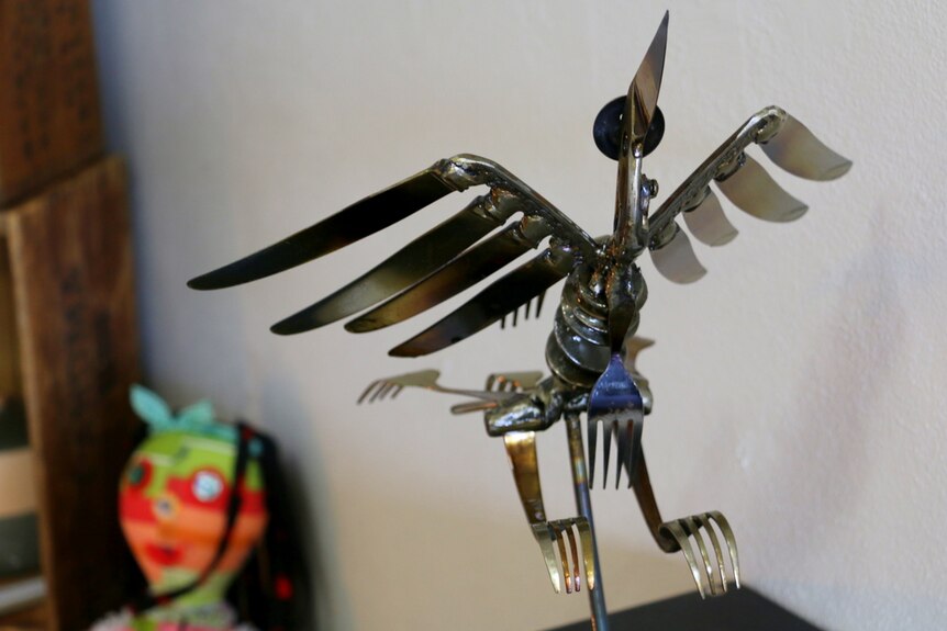 A metal sculpture of a bird has been made out of old knives and forks.