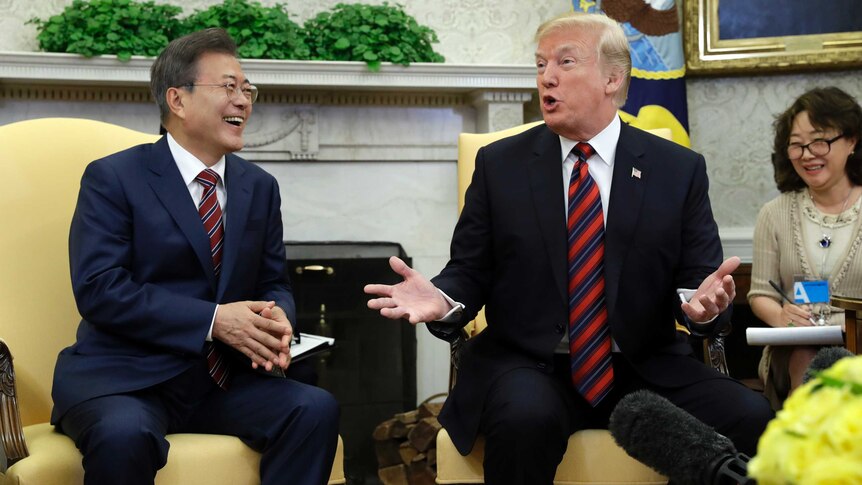 Moon Jae-in talks to Donald Trump who is gesturing.