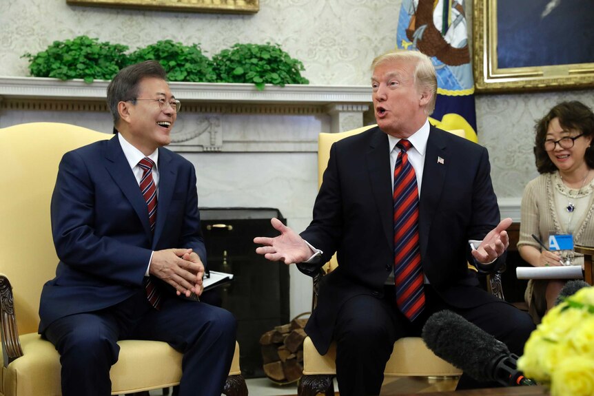 Moon Jae-in talks to Donald Trump who is gesturing.