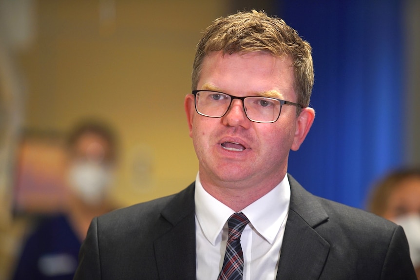 A man with reddish-brown hair wearing a suit and tie