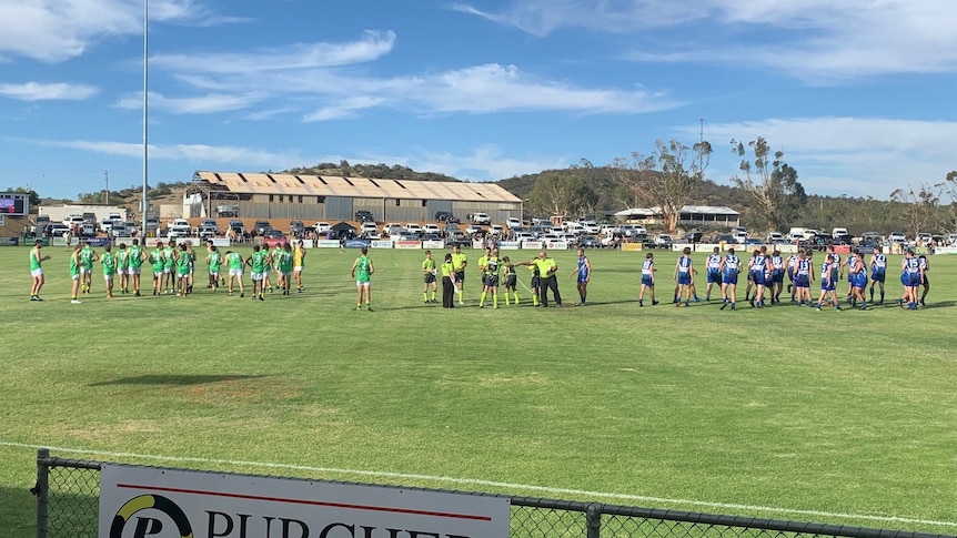 Football teams on an oval, warming up.