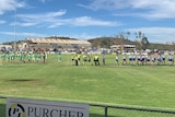 Football teams on an oval, warming up.
