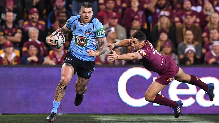 Josh Dugan of the NSW Blues gets past Maroons player Billy Slater to score.